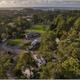 Aerial/drone view showing the campground layout, RVs, trees, central buildings and nearby coastline — valuable overall overview (from the About page).