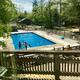 Clear daytime photo of the on-site swimming pool and surrounding deck/grounds, showing recreation facilities and campground layout (source: Campground / Recreation page).