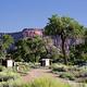A registration kiosk and and vault toilet under Cottonwood trees with red rock cliffs in the background.