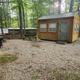 Another exterior cabin campsite view showing gravel pad, picnic table and surrounding trees — useful alternate angle of the same cabin area from the site’s ‘Our Resort’ gallery (cabin3.jpg).