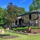 Photo showing RVs on gravel pads with decking, plantings and site flags — a clear view of the resort's RV sites. Image appears on the homepage/gallery background for RV Resort content.