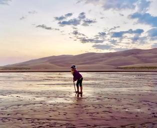 Person poses in front of sand dunes.