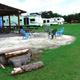 Shows on-site RVs, grassy common area and a fire pit with seating — clear photo of campground amenities and RV parking (filename IMG_0281 on the main site page).