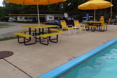 Poolside view showing the campground’s pool deck, umbrellas and nearby RV parking — useful facility shot (listed under campground activities/recreation).