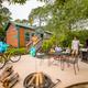 Photo of a cabin/lodge patio area with grill, table and fire pit — represents on‑site lodging amenities and outdoor campsite living (used on the page’s lodging imagery).