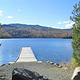 wooden dock stretching into the water with golden fall colors on the distant trees