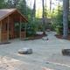 Wooden cabins in a forest setting with picnic tables and large rocks.