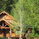 Front-facing view of a larger lodge/cabin building framed by trees — useful for showing the main accommodation architecture and setting.