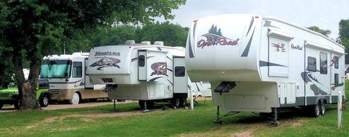 Row of RVs on gravel/grass pads illustrating typical RV sites and hookups; labeled on the page as RV sites so directly relevant.