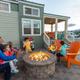 Image of a family gathered around a firepit on a paved patio by a cabin structure with RVs visible in the background — illustrates cabin lodging and shared outdoor amenities at the campground (from the site’s waystostay photos).