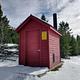 Red Outhouse, Surrounded by snow and green trees