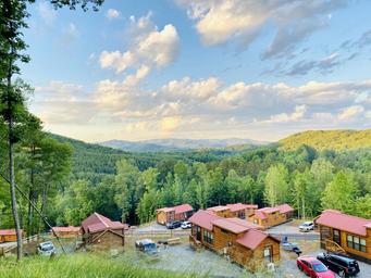 Hillside overview showing multiple cabins with red roofs and surrounding mountain scenery — good for illustrating lodging and scenic setting shown on the property pages.