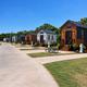 Row of onsite tiny homes/cabins with paved pads, picnic tables and utility pedestals — clear, high-quality photo from the property’s gallery highlighting cabin accommodations.