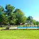 Outdoor swimming pool with fenced lawn, umbrellas and a building in the background — depicts on-site amenity shown on the campground’s rates/reservations page. Useful facilities image.