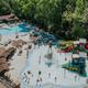 Aerial view of the resort’s large pool and water play area with slides and splash features — clear facility overview useful for a property gallery; matches site homepage pool/photos context.