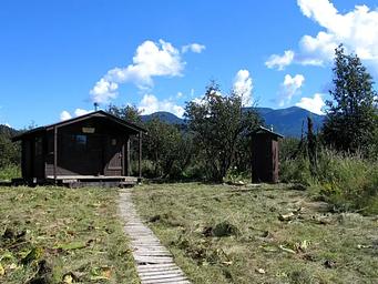 Koknuk Cabin with wooden trail leading to it and the outhouse