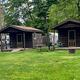 Photo of two small wooden cabins on grassy sites with picnic table and nearby RVs — directly shows the property’s cabin lodging option (page context: cabins).
