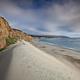 White sand dune next to a steep coastal bluff with ocean