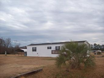 Exterior shot of a mobile home on open grounds with nearby amenities visible and natural sky — provides another angle of on-site housing and site layout (source: Rentals wrapper, rentimages/5.jpg).