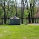 Yurt positioned near the river with grassy foreground and picnic table (Cherokee Rose Yurt) — demonstrates riverside campsite layout featured on the page.