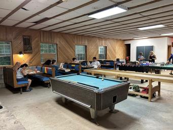 Interior of the recreation hall showing pool table, seating and activity space — represents on-site facilities and communal indoor amenities (from ‘Around the Camp’ page).