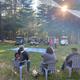 Evening gathering on a lawn with chairs, golf carts and pine trees — conveys community events and the wooded setting of the campground; sourced from the site's Activities page.