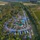 Aerial drone view clearly showing the campground layout: RV sites, roads, central buildings, pool, and surrounding woods — image is on the property homepage supporting its authenticity.
