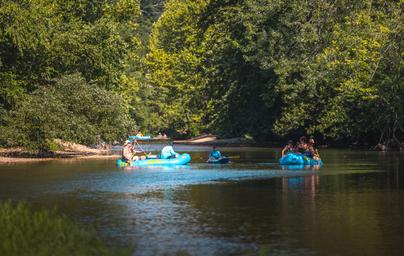 Scenic river image with people tubing on floats showcasing the resort’s river recreation; used on the homepage/river trip content.