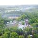Aerial overview showing campground layout: pool, buildings, cabins, pond and surrounding woods — source page is the property homepage with matching drone image file.