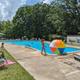 Outdoor swimming pool with chairs, umbrellas and guests — a clear facility photo. Image is labeled 'Pool' on the campground site, indicating it’s the property pool.