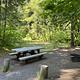 Campsite next to river with picnic table and firering