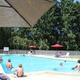Heated outdoor swimming pool in use with umbrellas and fencing — corresponds to the pool amenity described on the property site.