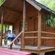 Close view of a rustic cabin with a covered porch and guests seated — useful for showing available cabin lodging and porch amenities on the property’s listing.