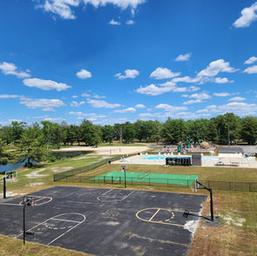 Wide scene showing recreational facilities including pool area, fenced courts and surrounding grounds — useful for guests evaluating on-site amenities (Gallery page).