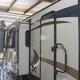RV repair technician sealing a window on a travel trailer slide out
