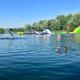 Bright waterfront photo showing the swim area, inflatables and treed shoreline — useful alternative angle of the main lake amenity used on the site's Lake Park gallery.