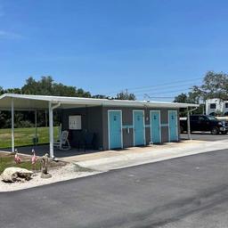 Cluster of restroom/shower stalls and covered walkway beside paved road — shows guest amenities and site layout; from the Gallery (IMG_0081).