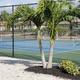 Tennis courts behind a perimeter fence with landscaping — documents on‑site sports facilities available to residents/guests.