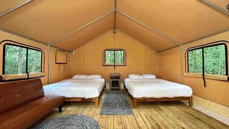 Interior of a glamping cabin/tent with beds and wood floor — useful to show on-site cabin accommodation (from resort accommodation/gallery pages).