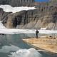 A man views rock cliffs above an alpine lake near Many Glacier