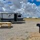 Photo of an RV/trailer pitch with picnic table and grill on a gravel pad — clearly shows the campground's RV/campsite offering and site amenities (used on the Camper Cabins / site pages).