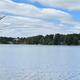 Scenic lake view across the water with shoreline trees and nearby buildings visible — directly relevant to the campground’s waterfront on the Our Water page.