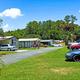 Street-level image of mobile homes and parked vehicles with landscaped lawns and trees — highlights residential units and onsite vehicle parking typical for the park (from the official site).
