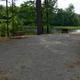 Gravel campsite pad with picnic table and direct view of the pond — useful to show an individual waterfront campsite and amenities.
