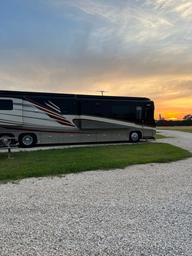 Large RV parked on a gravel pad at sunset — shows an RV site and surface type, useful for guests (appears on Rates & Policies page).