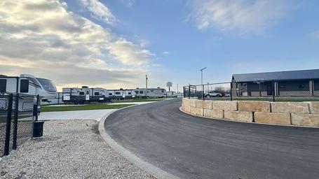 Ground-level view of RV sites and the access road with utility hookups and fencing — demonstrates typical RV pitch layout and infrastructure.