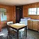 Cabin interior showing gas range, wood stove, table and dry sink.