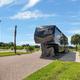 Paved RV pad with a fifth-wheel parked, landscaping and palm trees—useful depiction of an individual RV site and shown on the Plan Your Stay/gallery pages.