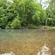 A view of Little Piney Creek, waterway in front with green vegatation in the background