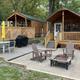 Two cabins with porches, outdoor furniture and paved patio area — clear photo of available cabin accommodations and appears in the campground’s 'ways to stay' gallery.